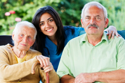 caregiver with senior man and woman smiling